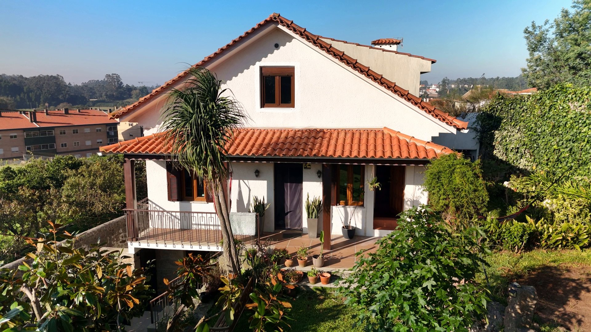 La casa con su tejado de teja, la terraza y el jardín, con el valle de Touguinhó al fondo